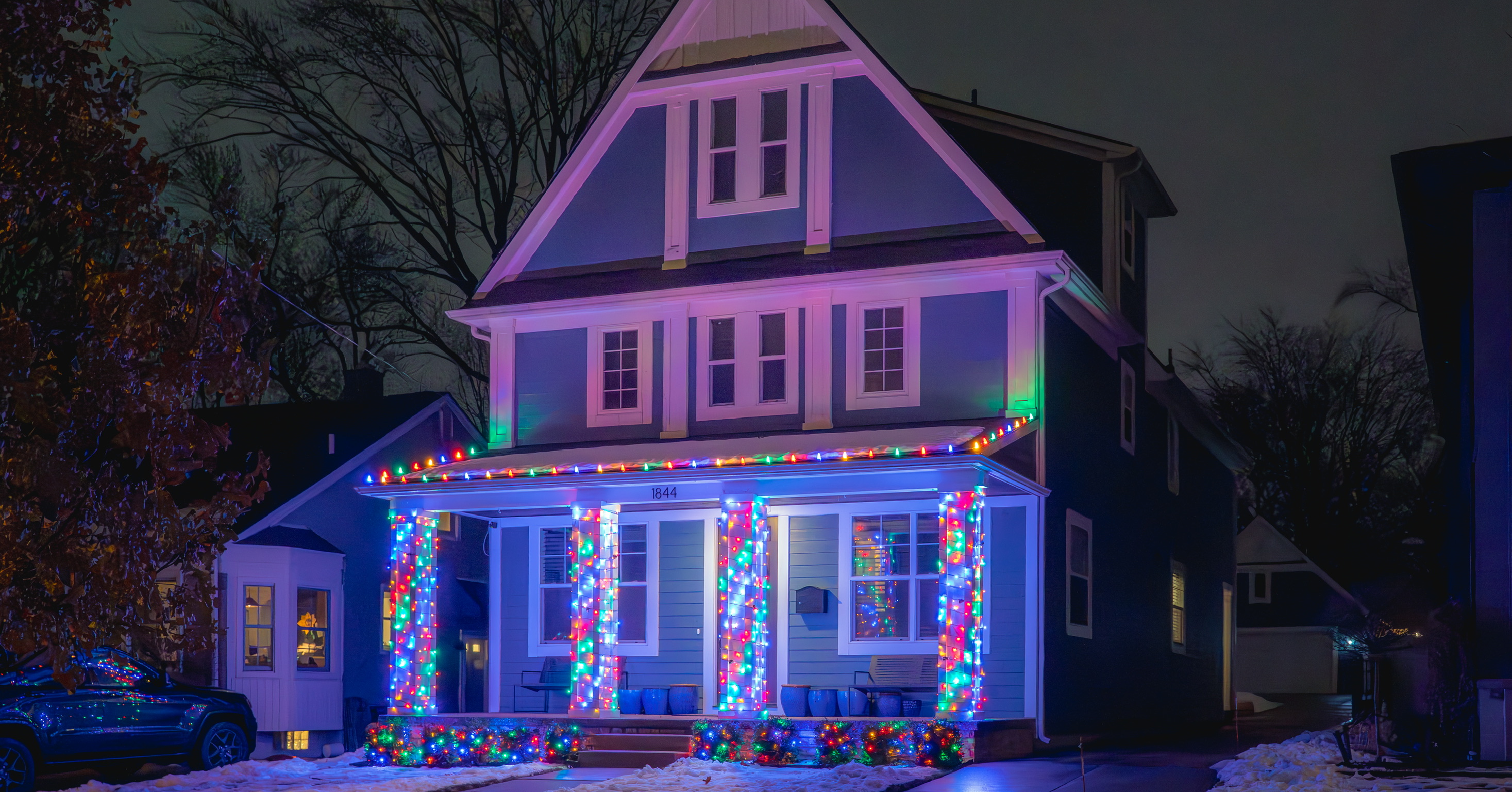 Home decorated with multicolored holiday lights around the porch and columns